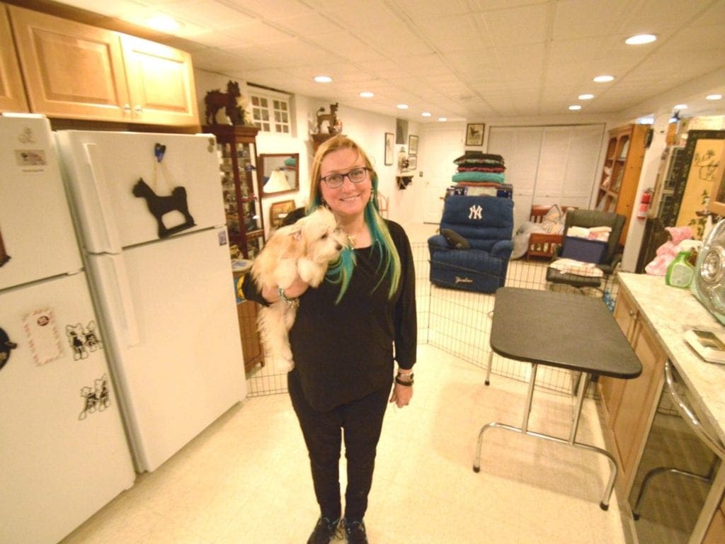Arlene Butterklee stands in her basement holding a powderpuff Chinese Crested puppy. Photo by Adam Aslan